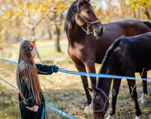 Obraz premium Happy girl stroking a horse, standing near the fence in the stable.