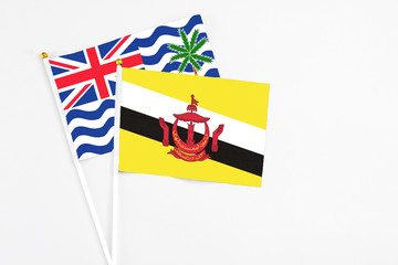 Brunei and British Indian Ocean Territory stick flags on white background. High quality fabric, miniature national flag. Peaceful global concept.White floor for copy space.