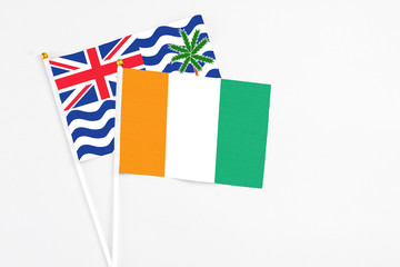 Cote D'Ivoire and British Indian Ocean Territory stick flags on white background. High quality fabric, miniature national flag. Peaceful global concept.White floor for copy space.