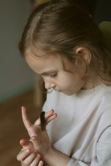 Fototapeta premium Portrait of a girl with curly hair who looks at a black caterpillar