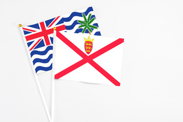 Fototapeta premium Jersey and British Indian Ocean Territory stick flags on white background. High quality fabric, miniature national flag. Peaceful global concept.White floor for copy space.