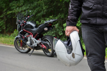 Naklejka premium Driver riding motorcycle on an asphalt road through forest.