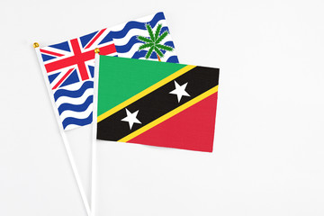 Saint Kitts And Nevis and British Indian Ocean Territory stick flags on white background. High quality fabric, miniature national flag. Peaceful global concept.White floor for copy space.