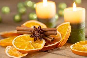 Christmas or advent decoration - candles with orange slices and spices on old wood
