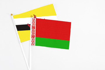 Belarus and Brunei stick flags on white background. High quality fabric, miniature national flag. Peaceful global concept.White floor for copy space.