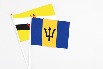 Barbados and Brunei stick flags on white background. High quality fabric, miniature national flag. Peaceful global concept.White floor for copy space.