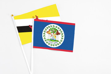 Belize and Brunei stick flags on white background. High quality fabric, miniature national flag. Peaceful global concept.White floor for copy space.