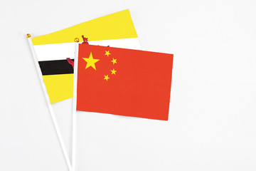 China and Brunei stick flags on white background. High quality fabric, miniature national flag. Peaceful global concept.White floor for copy space.
