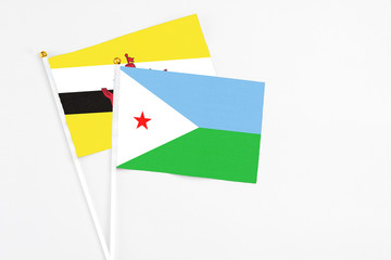 Djibouti and Brunei stick flags on white background. High quality fabric, miniature national flag. Peaceful global concept.White floor for copy space.