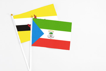 Equatorial Guinea and Brunei stick flags on white background. High quality fabric, miniature national flag. Peaceful global concept.White floor for copy space.