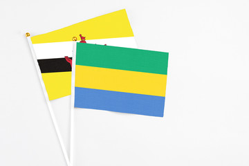 Gabon and Brunei stick flags on white background. High quality fabric, miniature national flag....