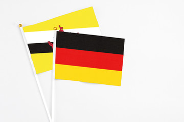 Germany and Brunei stick flags on white background. High quality fabric, miniature national flag. Peaceful global concept.White floor for copy space.