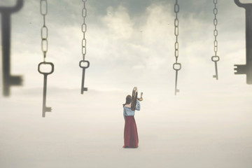 surreal image of a woman choosing a key among many hanging in the sky. Concept of solution, choice,...