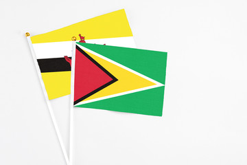 Guyana and Brunei stick flags on white background. High quality fabric, miniature national flag. Peaceful global concept.White floor for copy space.