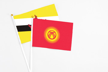 Kyrgyzstan and Brunei stick flags on white background. High quality fabric, miniature national flag. Peaceful global concept.White floor for copy space.