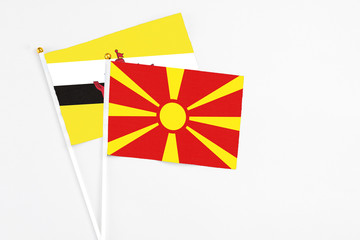 Macedonia and Brunei stick flags on white background. High quality fabric, miniature national flag. Peaceful global concept.White floor for copy space.