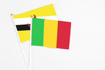 Mali and Brunei stick flags on white background. High quality fabric, miniature national flag. Peaceful global concept.White floor for copy space.