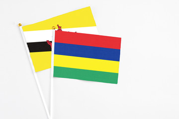 Mauritius and Brunei stick flags on white background. High quality fabric, miniature national flag. Peaceful global concept.White floor for copy space.