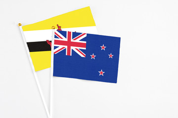Fototapeta premium New Zealand and Brunei stick flags on white background. High quality fabric, miniature national flag. Peaceful global concept.White floor for copy space.