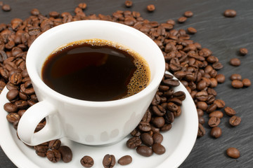 Hot coffee cup and coffee beans on black background top view
