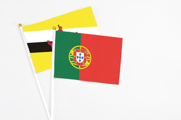 Portugal and Brunei stick flags on white background. High quality fabric, miniature national flag. Peaceful global concept.White floor for copy space.