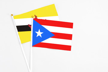 Puerto Rico and Brunei stick flags on white background. High quality fabric, miniature national flag. Peaceful global concept.White floor for copy space.