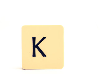 Dark letter K on a pale yellow square block isolated on white background