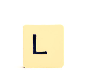 Dark letter L on a pale yellow square block isolated on white background