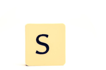Dark letter S on a pale yellow square block isolated on white background