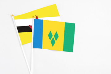 Saint Vincent And The Grenadines and Brunei stick flags on white background. High quality fabric, miniature national flag. Peaceful global concept.White floor for copy space.