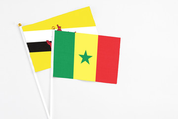 Naklejka premium Senegal and Brunei stick flags on white background. High quality fabric, miniature national flag. Peaceful global concept.White floor for copy space.