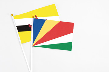 Seychelles and Brunei stick flags on white background. High quality fabric, miniature national flag. Peaceful global concept.White floor for copy space.