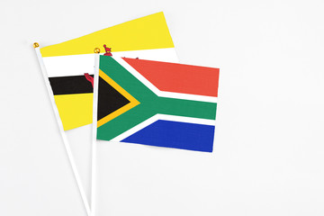 South Africa and Brunei stick flags on white background. High quality fabric, miniature national flag. Peaceful global concept.White floor for copy space.