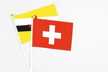 Switzerland and Brunei stick flags on white background. High quality fabric, miniature national flag. Peaceful global concept.White floor for copy space.