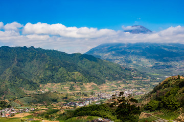 Naklejka premium Spokojne miasteczko otoczone górami i pięknym błękitnym niebem