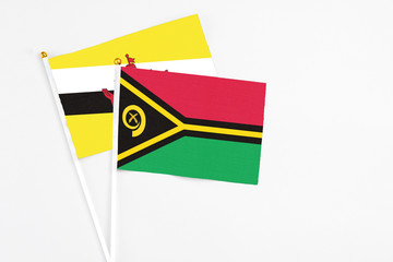 Vanuatu and Brunei stick flags on white background. High quality fabric, miniature national flag. Peaceful global concept.White floor for copy space.