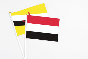 Yemen and Brunei stick flags on white background. High quality fabric, miniature national flag. Peaceful global concept.White floor for copy space.