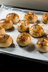 Homemade Turkish Pastries Pogaca with Black Cumin and Sesame Seeds on Baking Paper Sheet with Tray.
