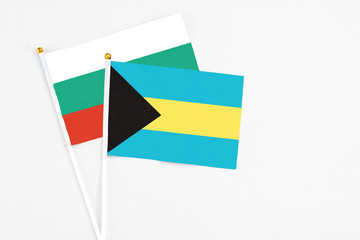 Bahamas and Bulgaria stick flags on white background. High quality fabric, miniature national flag. Peaceful global concept.White floor for copy space.
