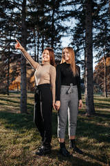 Charming two young twin sisters in casual outfit with bright smile posing at the park.