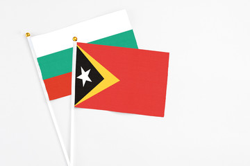 East Timor and Bulgaria stick flags on white background. High quality fabric, miniature national flag. Peaceful global concept.White floor for copy space.