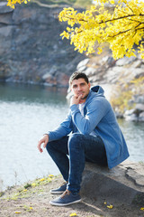 Obraz premium Young man by the lake in autumn day.