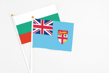 Fototapeta premium Fiji and Bulgaria stick flags on white background. High quality fabric, miniature national flag. Peaceful global concept.White floor for copy space.
