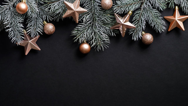 Christmas banner. Xmas tree branches decorated cooper stars and balls on black background. Flat lay, top view, copy space. New year, winter holidays, Christmas concept.