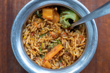 Navratan saffron biryani in metal pot on wooden background, top view, close up. Indian cuisine