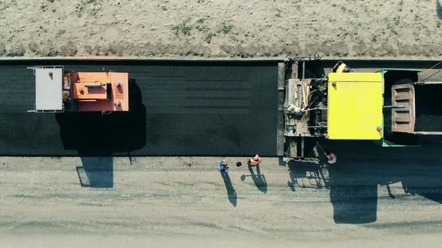 Fresh bitum is getting leveled out by the workers and machines