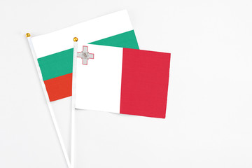 Malta and Bulgaria stick flags on white background. High quality fabric, miniature national flag. Peaceful global concept.White floor for copy space.