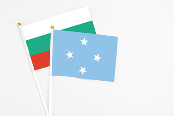 Micronesia and Bulgaria stick flags on white background. High quality fabric, miniature national flag. Peaceful global concept.White floor for copy space.