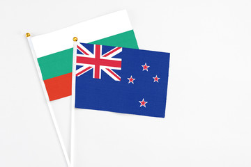 Fototapeta premium New Zealand and Bulgaria stick flags on white background. High quality fabric, miniature national flag. Peaceful global concept.White floor for copy space.