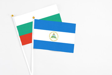 Nicaragua and Bulgaria stick flags on white background. High quality fabric, miniature national flag. Peaceful global concept.White floor for copy space.